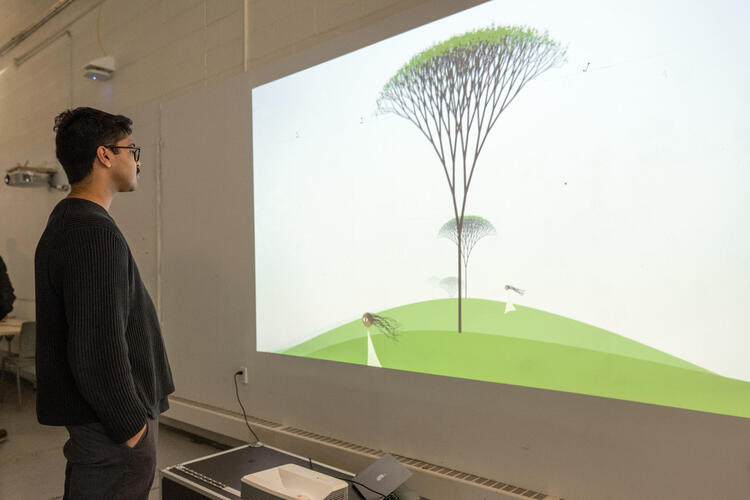 Photo of an attendee viewing the animated piece, which features ever-looping scene of a young girl with long curly hair standing in front of a tree.