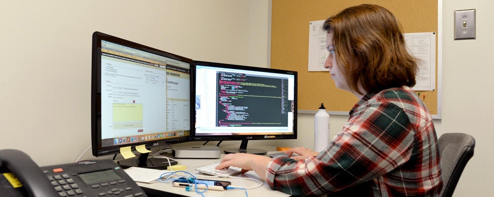 A co-op student (Jamie) works on some code at a mac workstation.