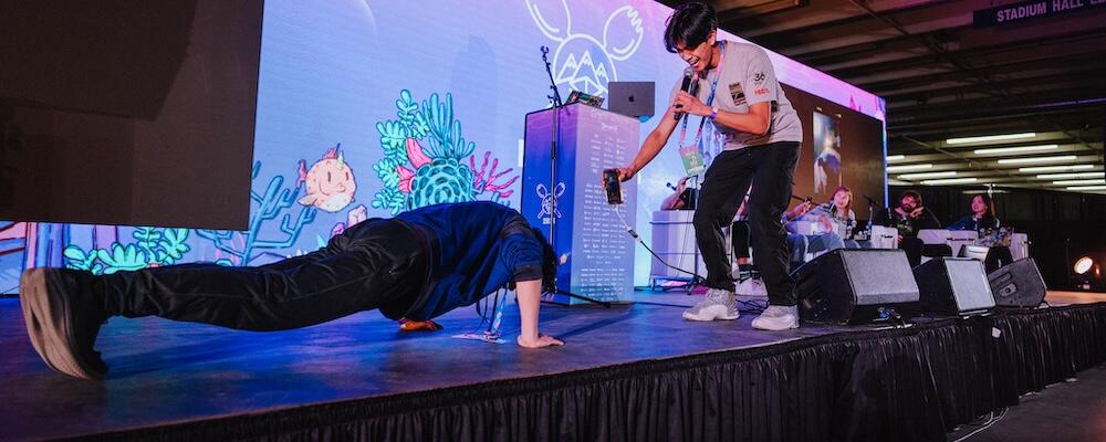 William Wang performing 10 push-ups as his teammate Xavier cheers him on during the duo's pitch for the closing ceremony