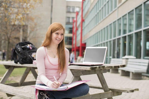 female student studying outside on a park bench