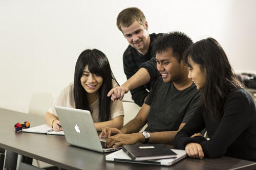 four students working from a lap top