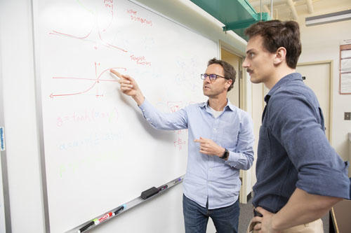 Professor and student solving a problem on a white board