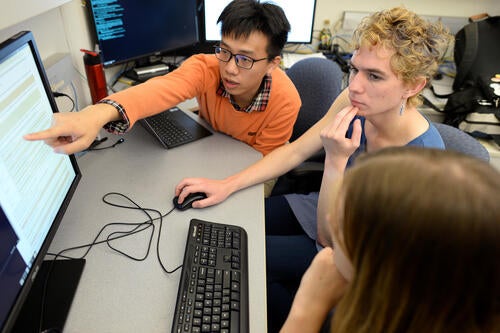 Image of three students working at a computer station together