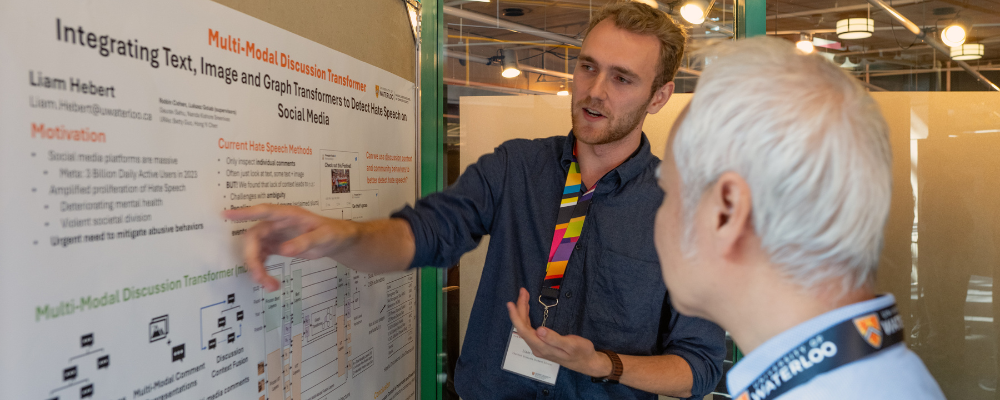 PhD student Liam Hebert presenting his research poster to a computer science professor