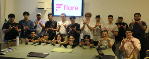 Photo of the Waterloo Blockchain standing in front of a screen and doing the "W" hand sign 
