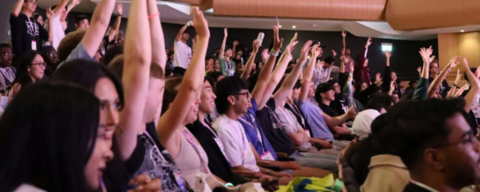 photo of audience members raising their hands