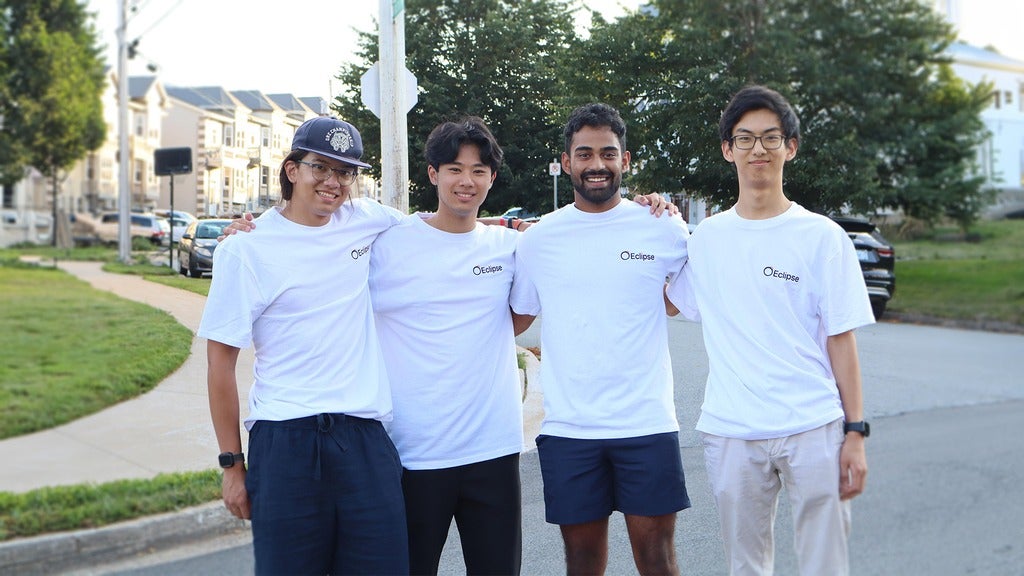 group shot of Eclipse founders donning their Eclipse merch (white shirts with company name). They are standing in a suburb area