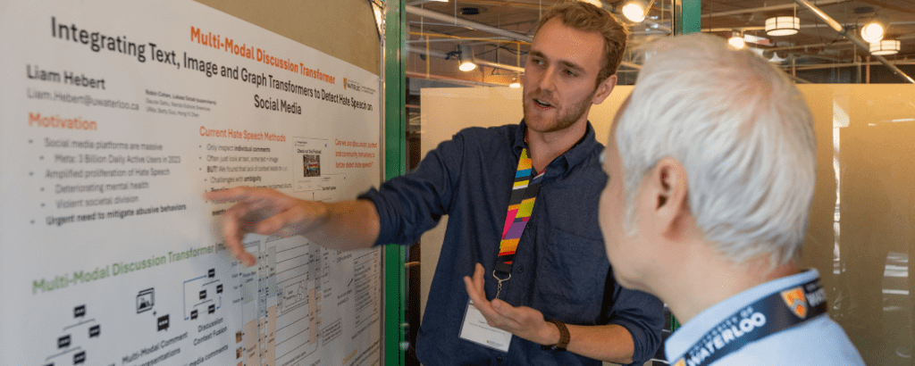 PhD student Liam Hebert presenting his research poster to a computer science professor
