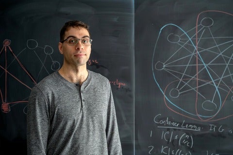 PhD candidate Cameron Seth at a blackboard