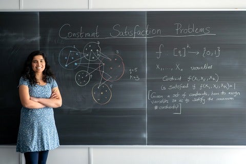 Professor Santhoshini Velusamy stands in front of a blackboard