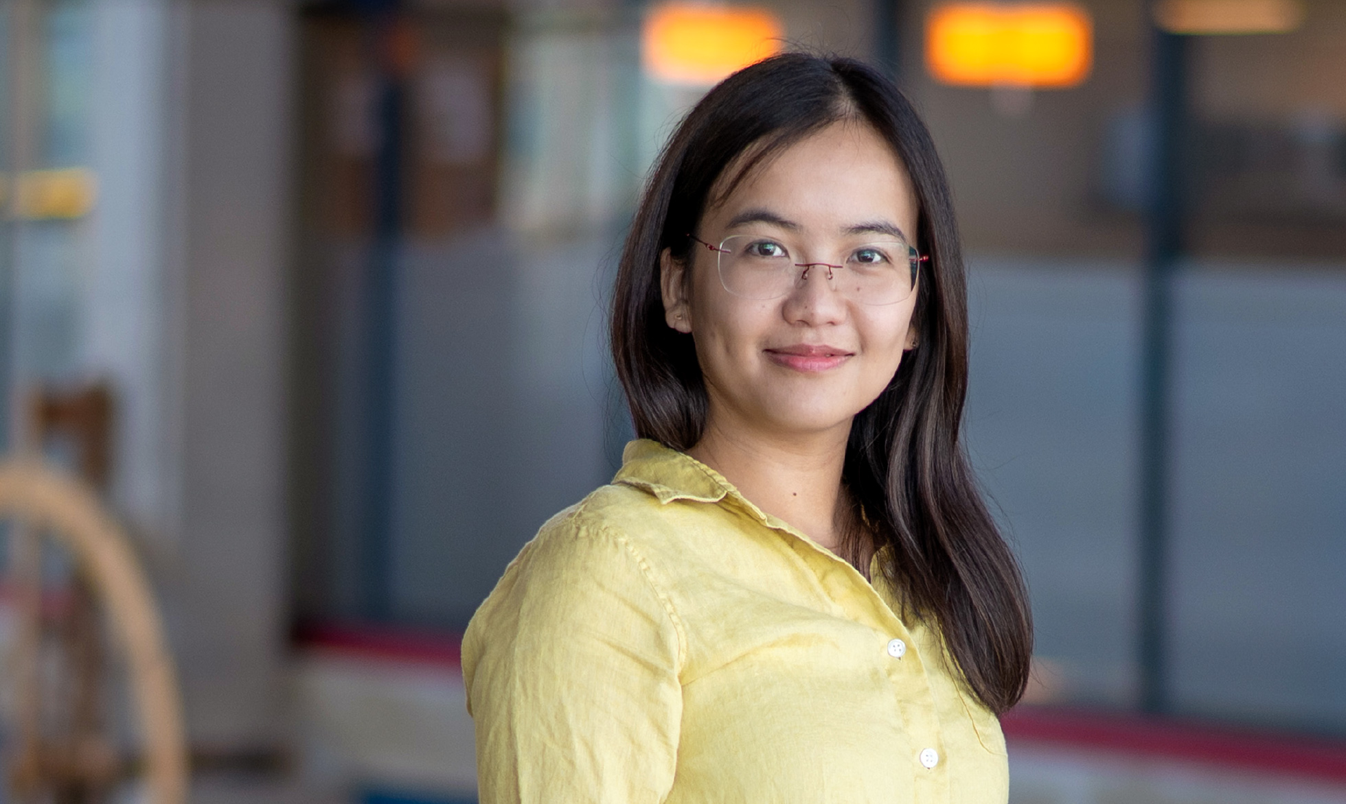 An asian women wearing glasses and a long sleeve yellow dress shirt