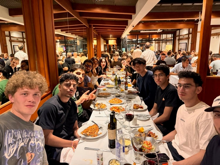 blockchain club sitting at a very long white-tabled cloth table inside a restaurant that has brown interior