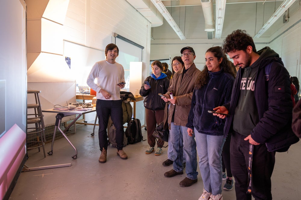 A group of people holding phones and standing in front of a screen 