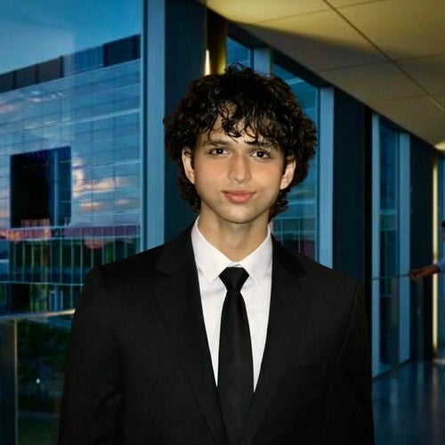 An Indian man in a suit and tie posing at the E7 bridge. The photo has yellow and blue saturation